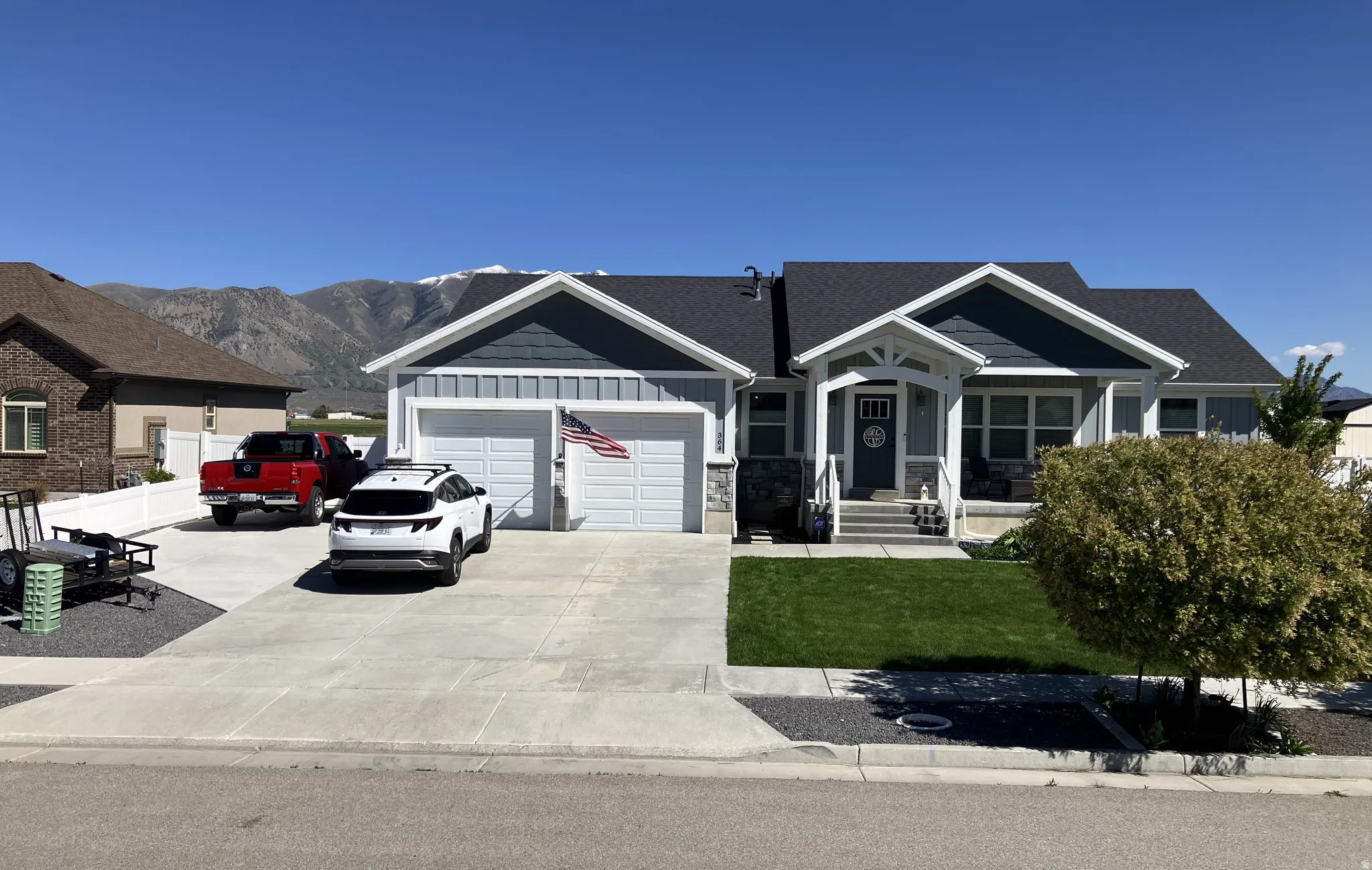 Ranch-style exterior with gray siding, a two-car garage, and a covered front porch with white columns