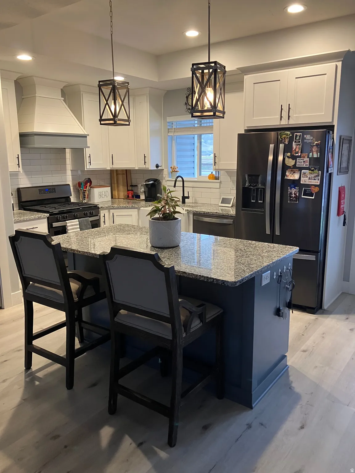 Kitchen featuring a central island with a granite-style countertop, stainless steel appliances, white subway tile backsplash, white shaker-style cabinetry, and recessed lighting