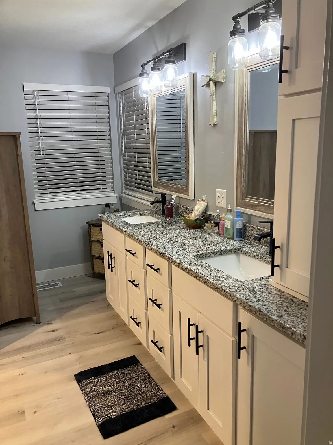 Dual sink vanity featuring light-toned cabinetry and black hardware