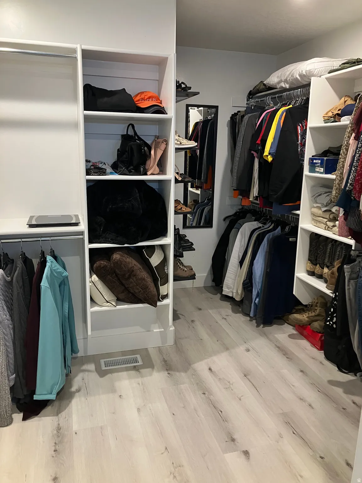 Custom built-in white shelving, wood-finish flooring, and ample hanging rod space
