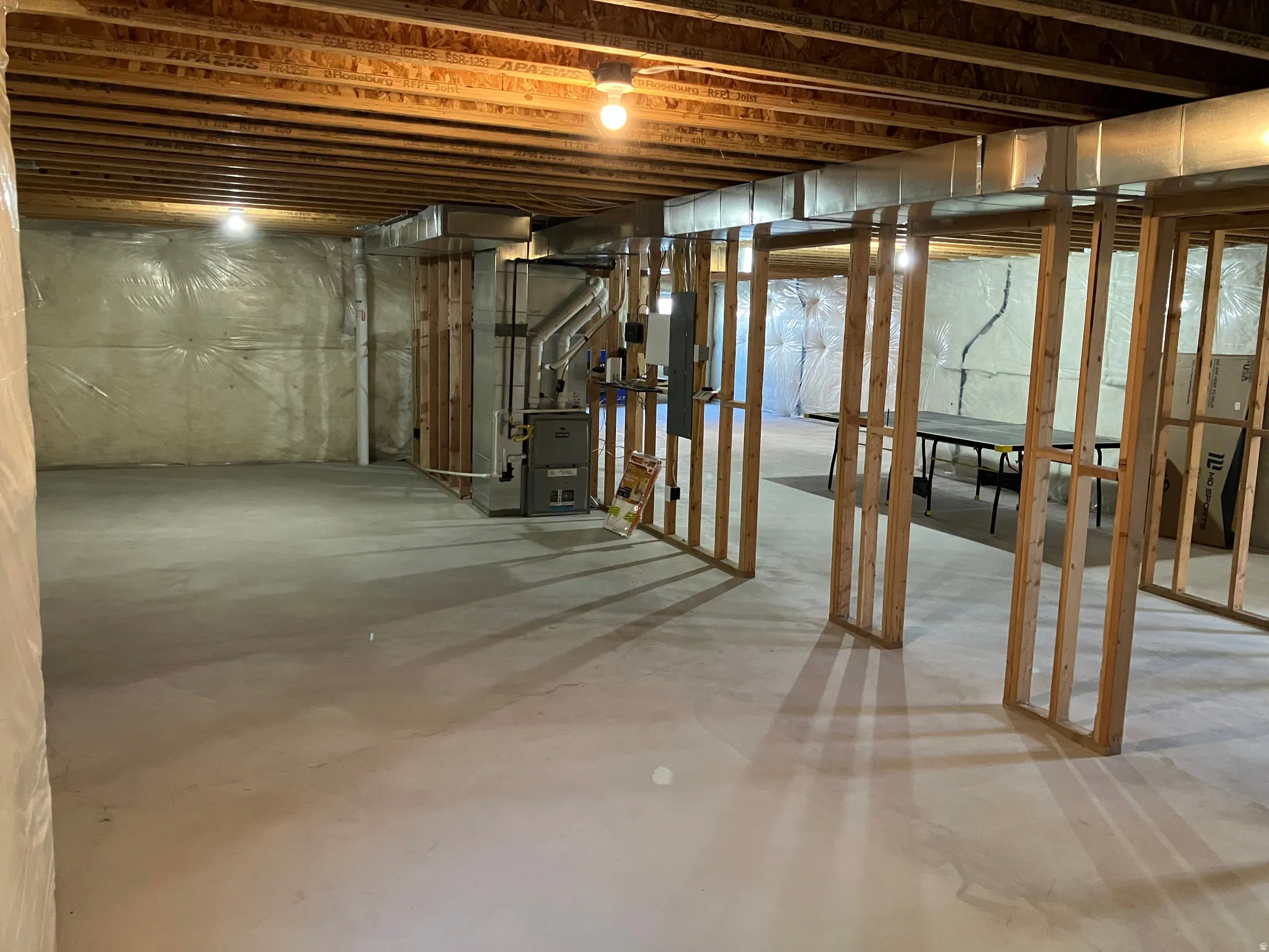 Unfinished lower level with wood framing, exposed ceiling joists, and concrete flooring