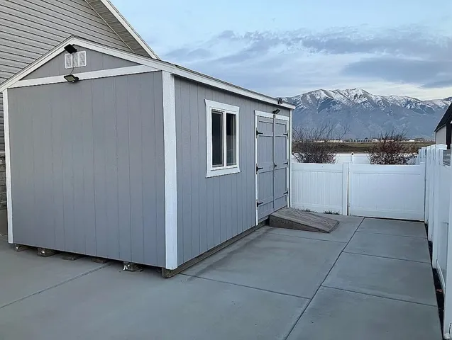 Detached shed with light gray siding, a single window, and double doors featuring black hardware