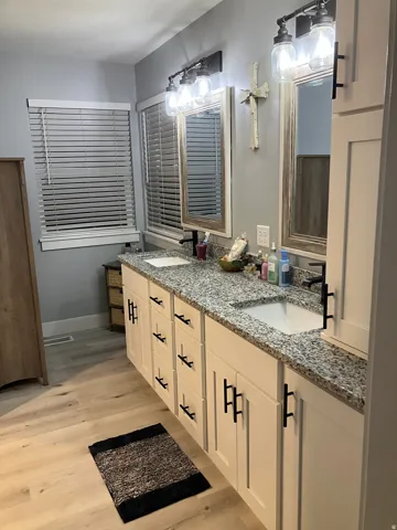Dual sink vanity featuring light-toned cabinetry and black hardware