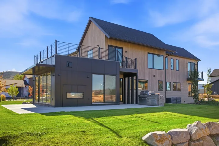 Modern exterior with extensive glazing, wood-finish siding, and a spacious rooftop deck