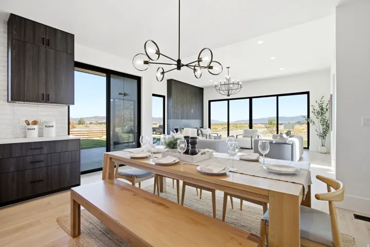 Open concept living space featuring a wood-finish dining table and bench seating, a modern chandelier, and large sliding glass doors