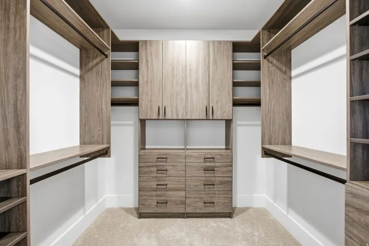 Built-in closet system featuring wood-finish cabinetry, integrated shelving, hanging rods, and multiple drawers