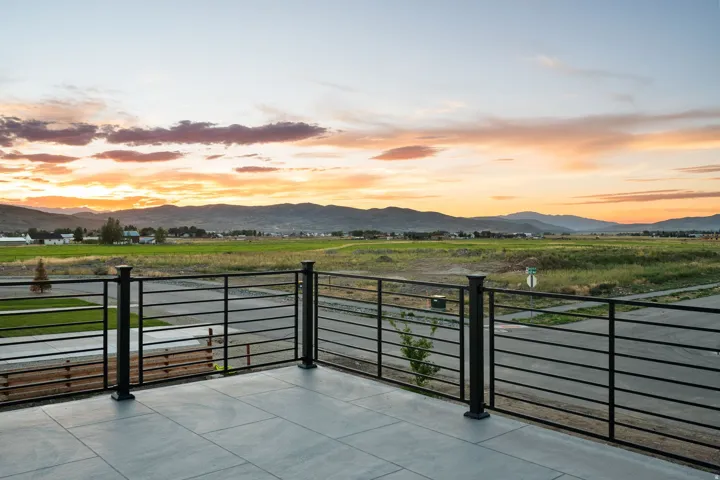 Concrete patio with a black metal railing and mountain scenery