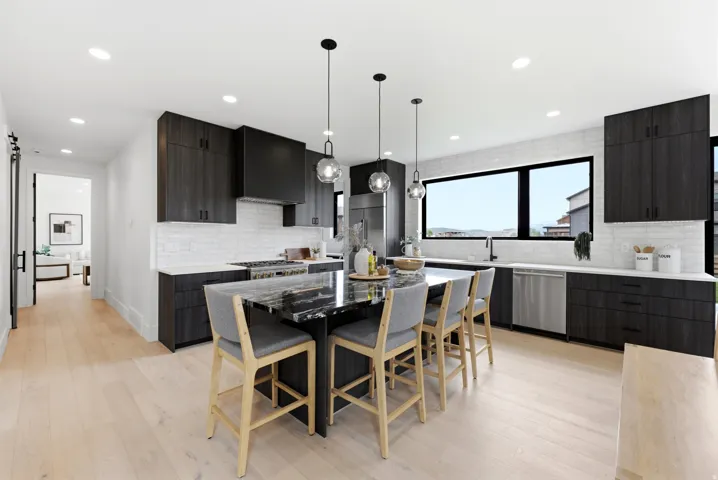 Kitchen with a dark wood-finish cabinetry, a large center island with a stone countertop, stainless steel appliances, a tile backsplash, and light wood-finish flooring