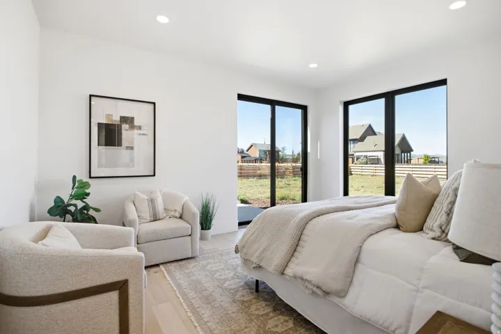 Recessed lighting, light wood-finish flooring, white walls, and multiple large windows with black frames