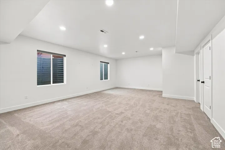 Spacious room with recessed lighting, two white panel doors, and two windows