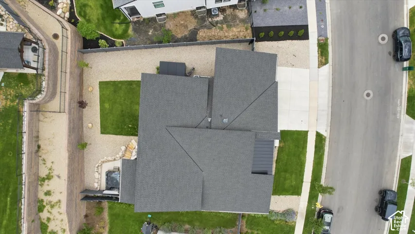 Asphalt shingle roofing, concrete driveway, gravel landscaping, manicured lawn, and retaining walls