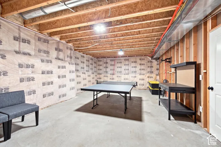 Unfinished basement featuring exposed wood joists, concrete flooring, and stud-framed walls