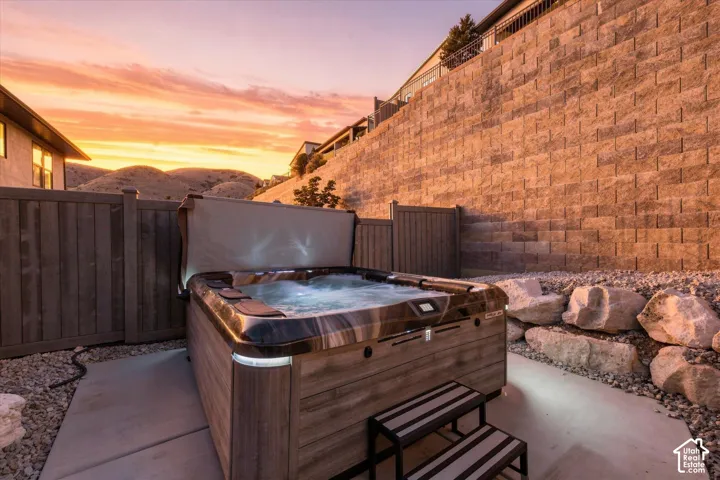 Outdoor spa with a cover lifter, two-step access, and surrounding concrete pad
