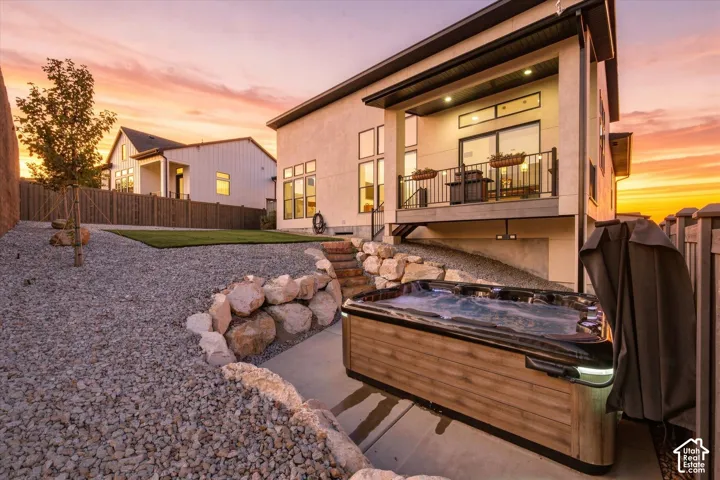 Outdoor spa with wood-finish siding, multi-level landscaping with gravel and artificial turf, and a private deck with a metal railing