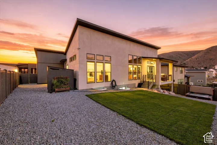 Contemporary-style exterior with extensive window placements, terraced backyard, covered outdoor living space, and a gravel hardscape area