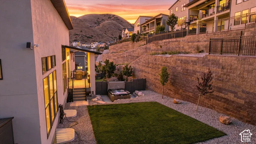 Private backyard featuring a manicured lawn, gravel landscaping, and a built-in hot tub