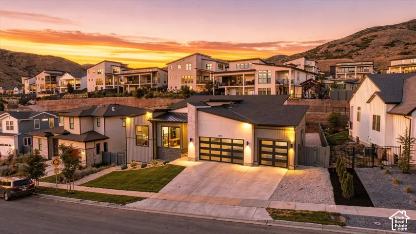 Contemporary exterior with a multi-pane garage door, concrete driveway, stone accents, and a manicured lawn