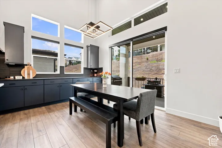 Vaulted ceilings, wood-finish flooring, dark cabinetry, modern chandelier, and sliding glass door to outdoor area