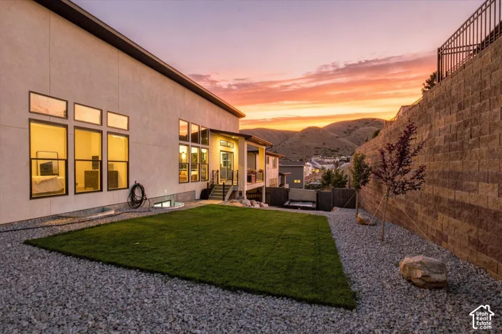 Expansive backyard with a manicured lawn, gravel landscaping, and a substantial stone retaining wall
