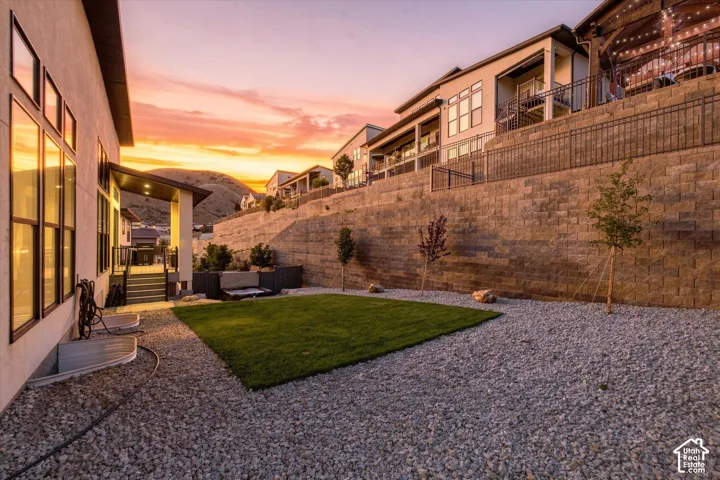 Expansive backyard featuring a manicured lawn, gravel landscaping, and a retaining wall