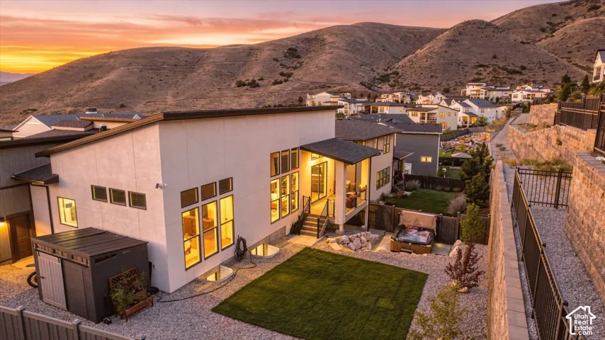 Modern exterior with multiple windows, leading to a landscaped backyard featuring a grass area and a built-in spa