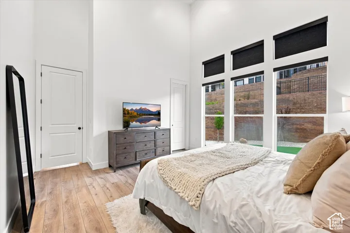 High ceilings, wood-finish flooring, multiple windows with black roller shades, and a built-in dresser with nine drawers