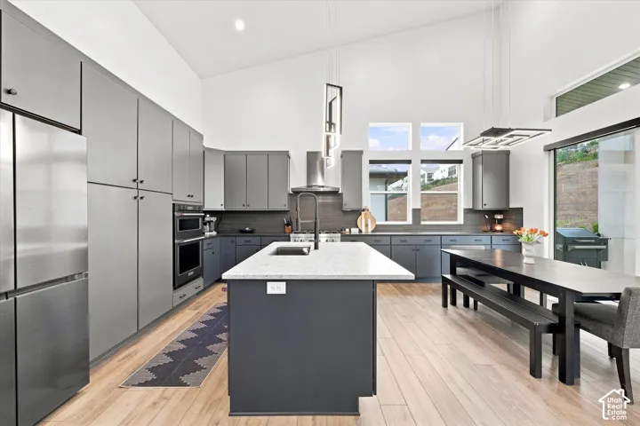 Open-concept kitchen with vaulted ceilings, light wood-finish flooring, and a large central island
