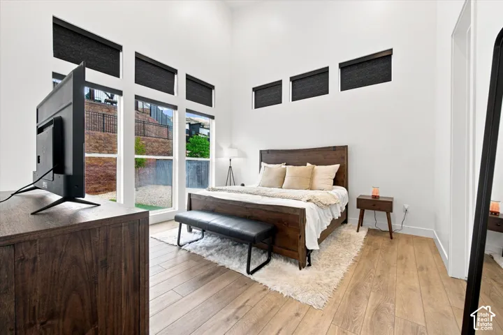 Room featuring vaulted ceilings, wood-finish flooring, and multiple large windows with integrated shades