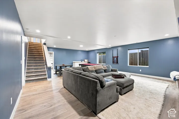 Spacious entertainment area featuring wood-finish flooring, recessed lighting, and a built-in wet bar with a sink and white cabinetry