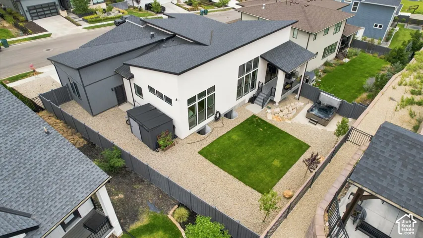 Modern-style residence with a dark shingle roof, white and dark gray siding, and an expansive gravel yard featuring a square lawn