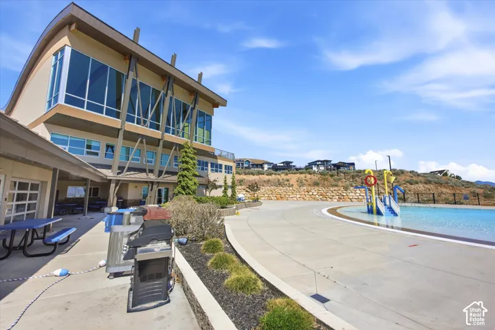Multi-level building with expansive windows, a large outdoor pool, and a dedicated splash pad area