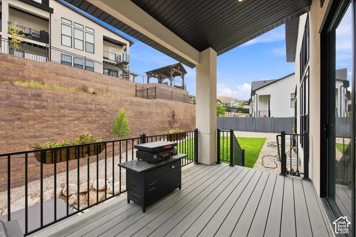 Covered outdoor patio with composite decking, black metal railings, and a retaining wall