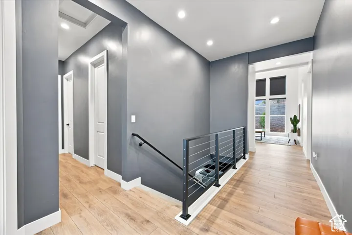 Wood-finish flooring, recessed lighting, white trim, and a contemporary cable railing system