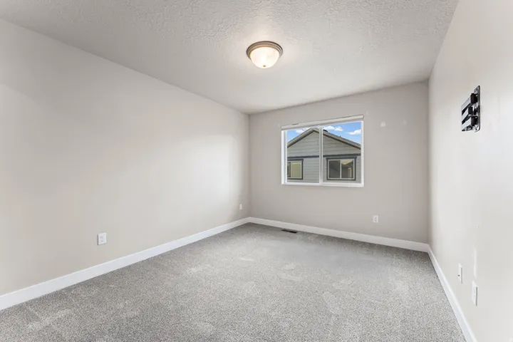 Neutral wall paint, gray carpeting, single window, flush mount ceiling light, and white trim