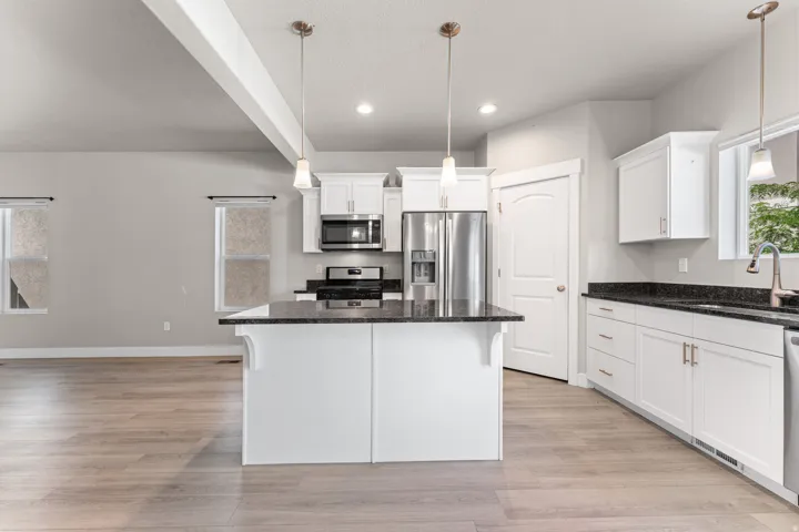 Kitchen featuring a central island, white cabinetry, dark stone countertops, and stainless steel appliances
