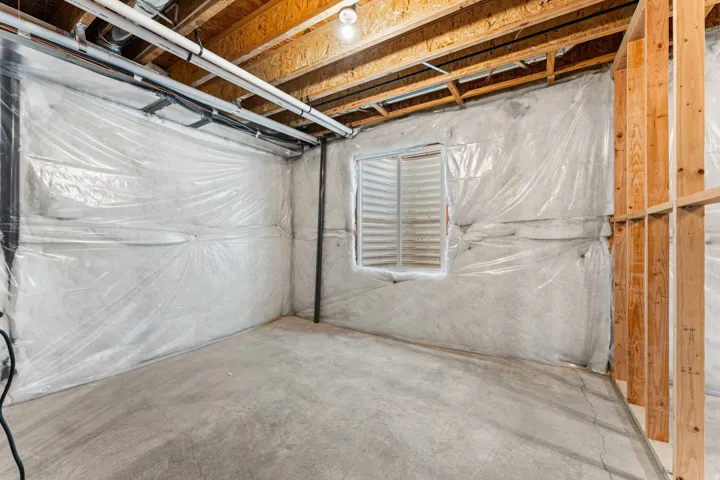 Concrete flooring with exposed ceiling joists, framed wall sections, and a window opening