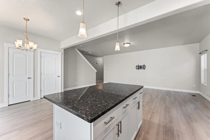 Kitchen island with dark countertop, white cabinetry with hardware, recessed lighting, and wood-finish flooring throughout