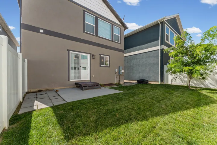 Backyard featuring a privacy fence, concrete patio, and mature tree