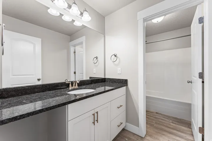 Vanity with dark countertop, integrated sink, and brushed nickel fixtures