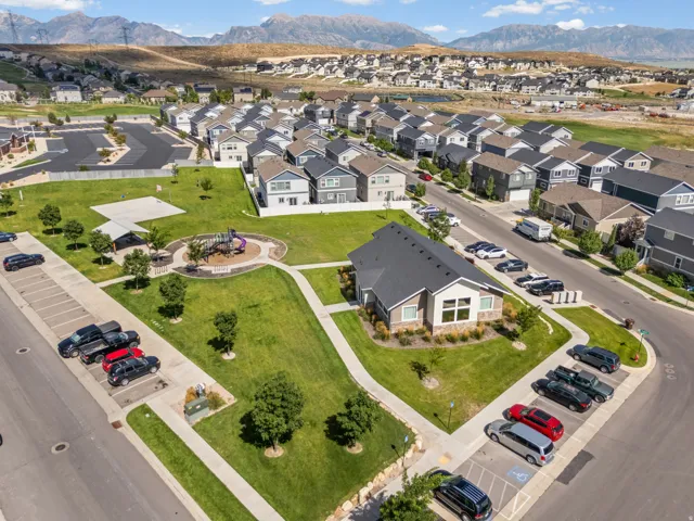 Community greenspace featuring a playground, shade structure, and paved walking paths