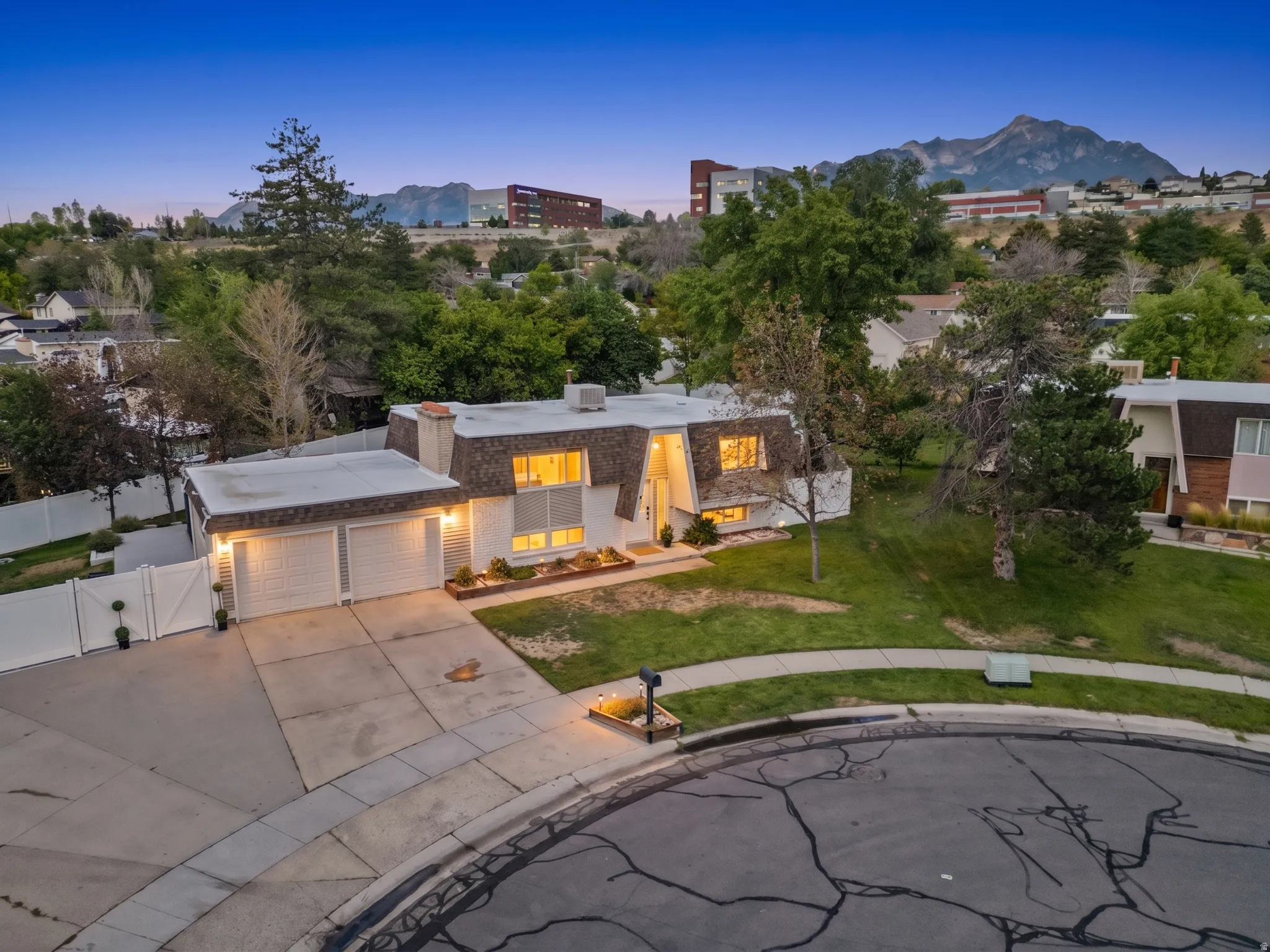 Mid-century modern exterior with a two-car garage, mature landscaping, and a sloped front yard