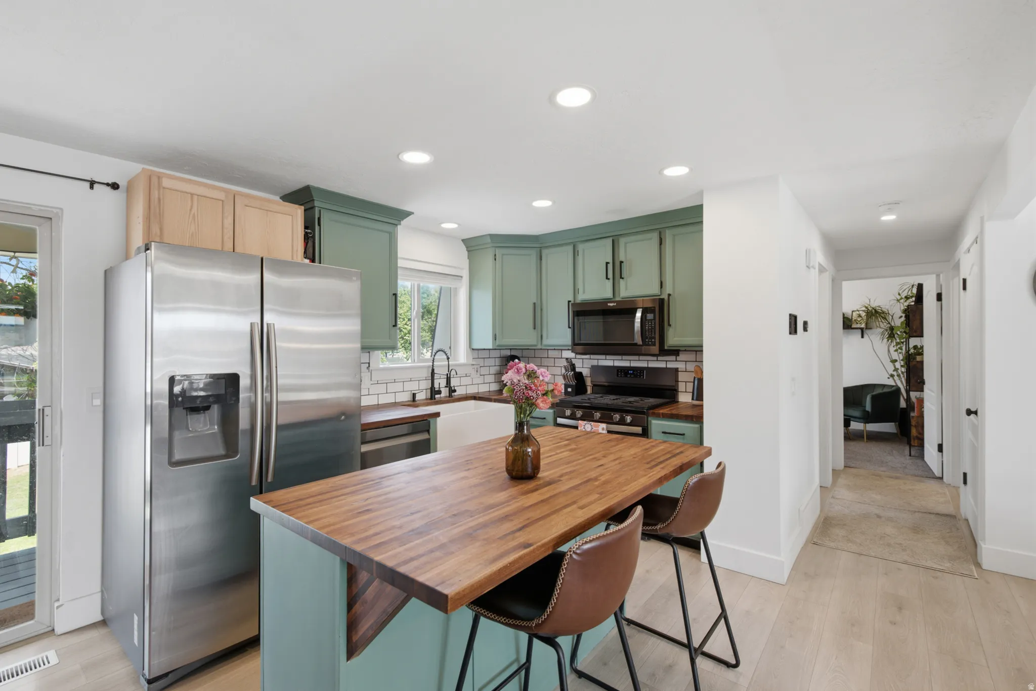 Kitchen featuring a wood-finish island, paneled cabinetry, stainless steel refrigerator, and built-in microwave