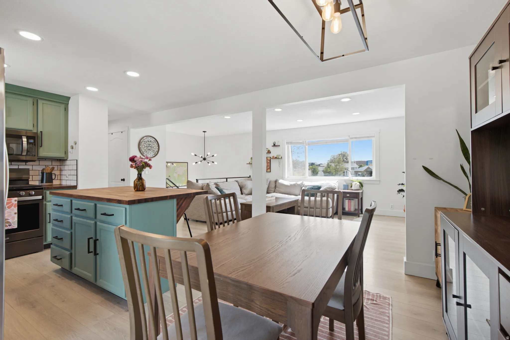 Open-concept living area with light wood-finish flooring, recessed lighting, and a kitchen island with a butcher block countertop