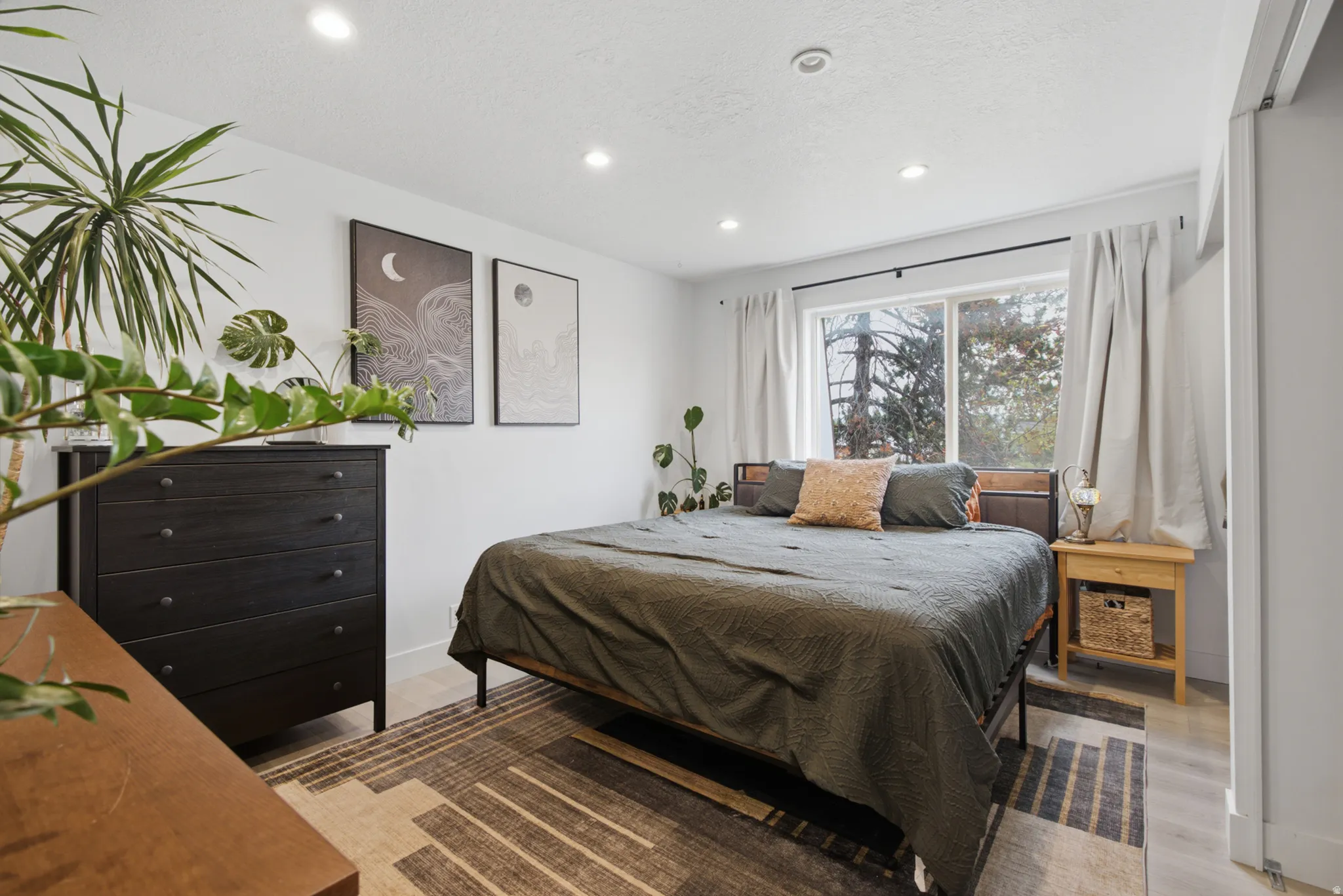 Recessed lighting, light wood-finish flooring, and a large window with white trim