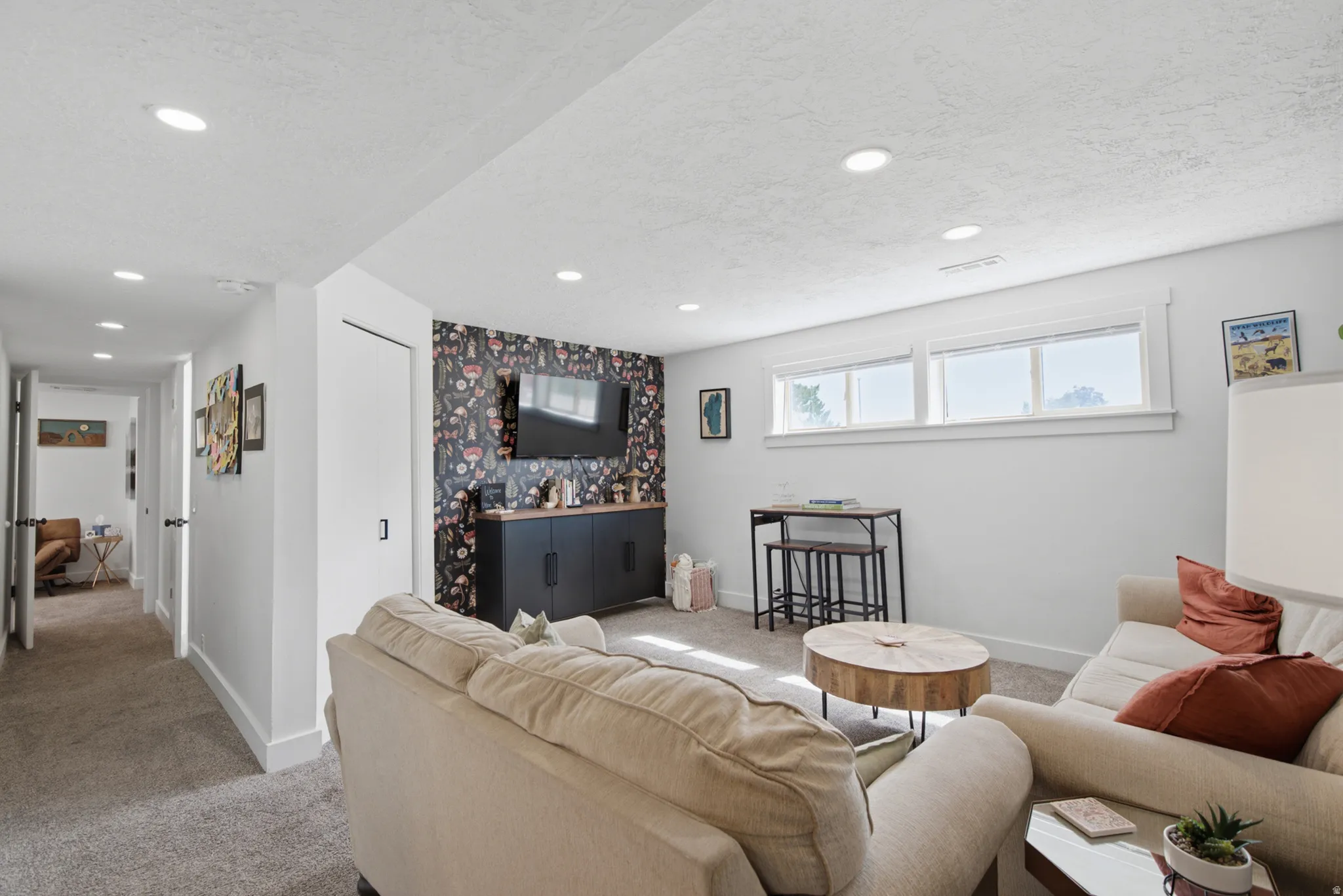 Recessed lighting, carpeted flooring, built-in media console, three transom windows, and a hallway with additional lighting