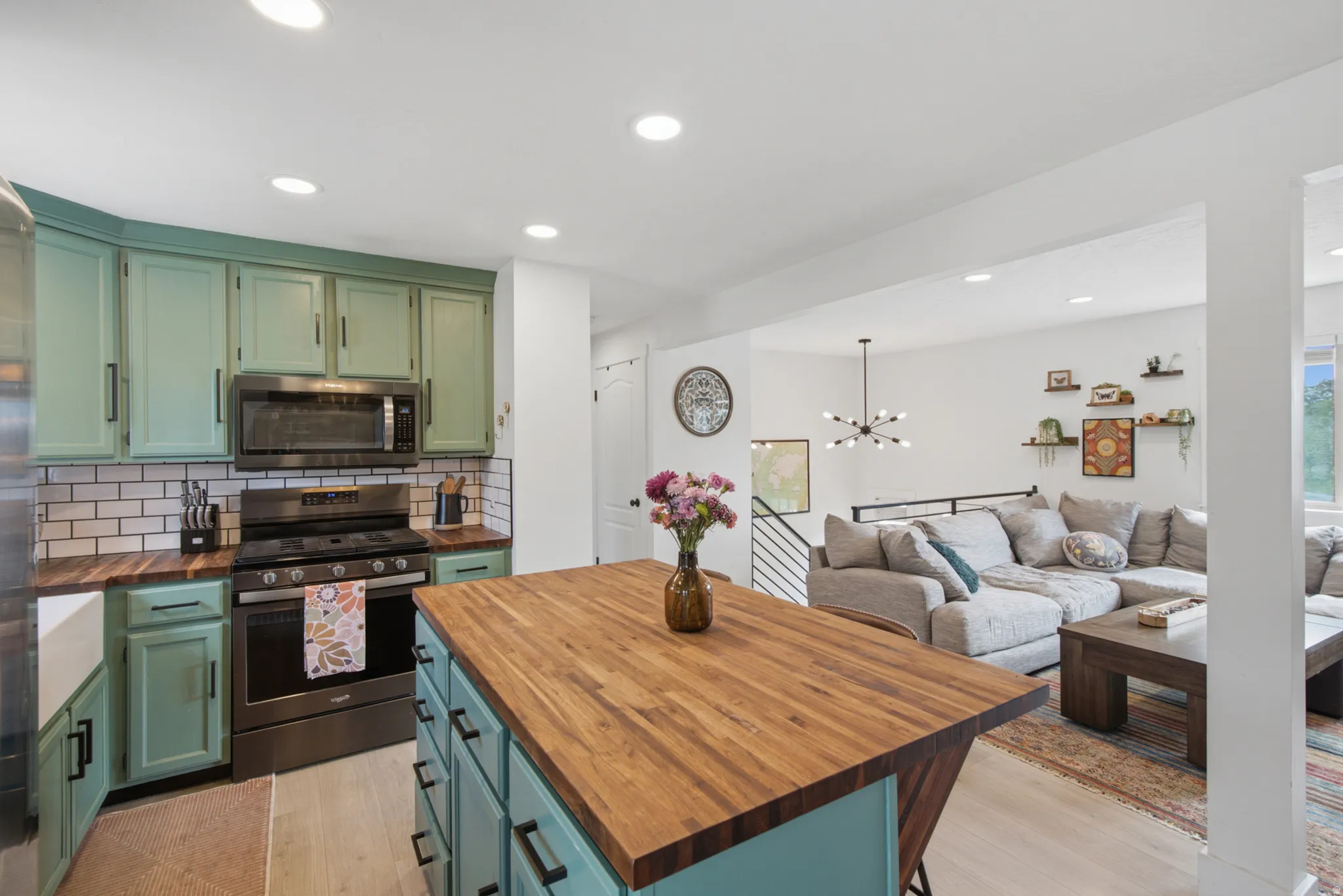 Kitchen with painted cabinetry, subway tile backsplash, and wood-finish countertops