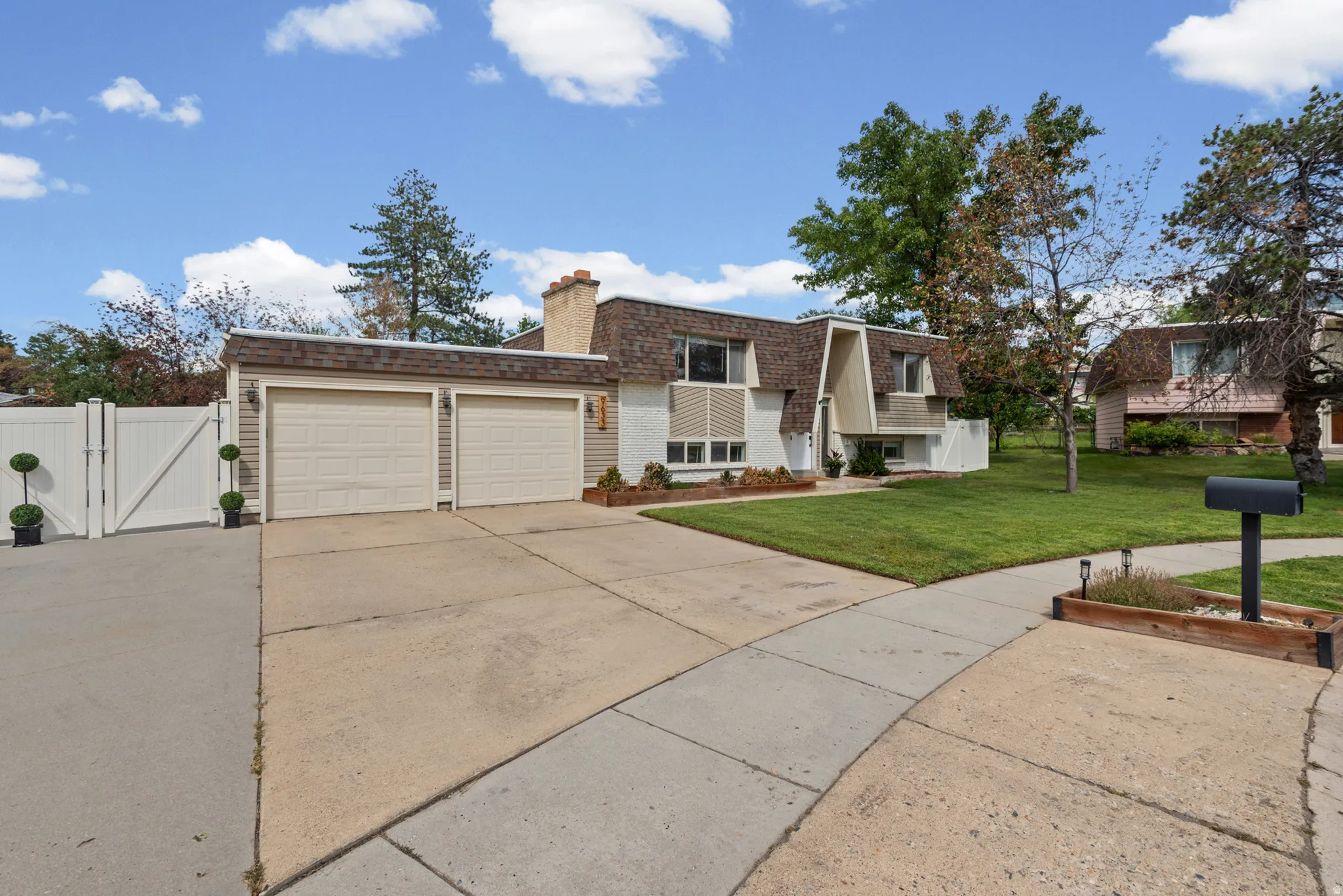 Gabled roofline with a prominent chimney, two-car garage, concrete driveway, and front lawn