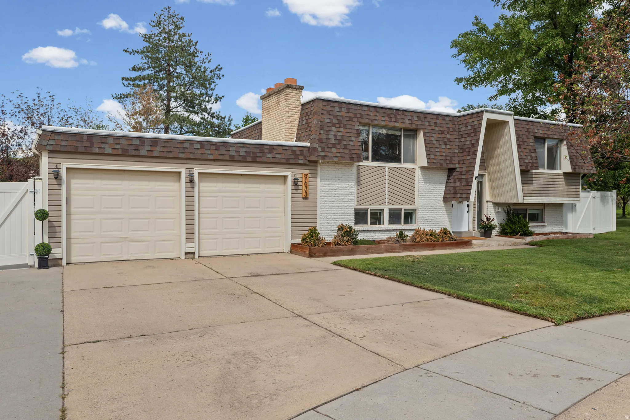 Two-car garage with panel doors, textured siding, and a gabled roof