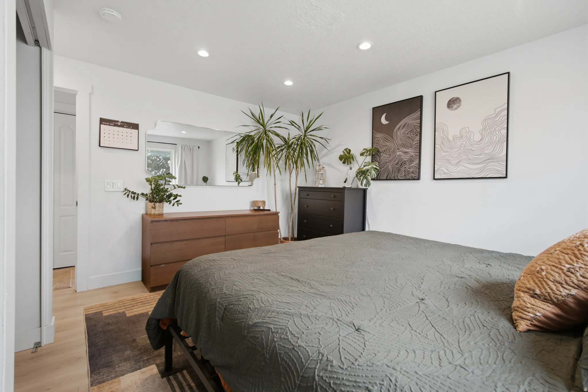 Recessed lighting, light wood-finish flooring, white walls, and a built-in closet with sliding doors