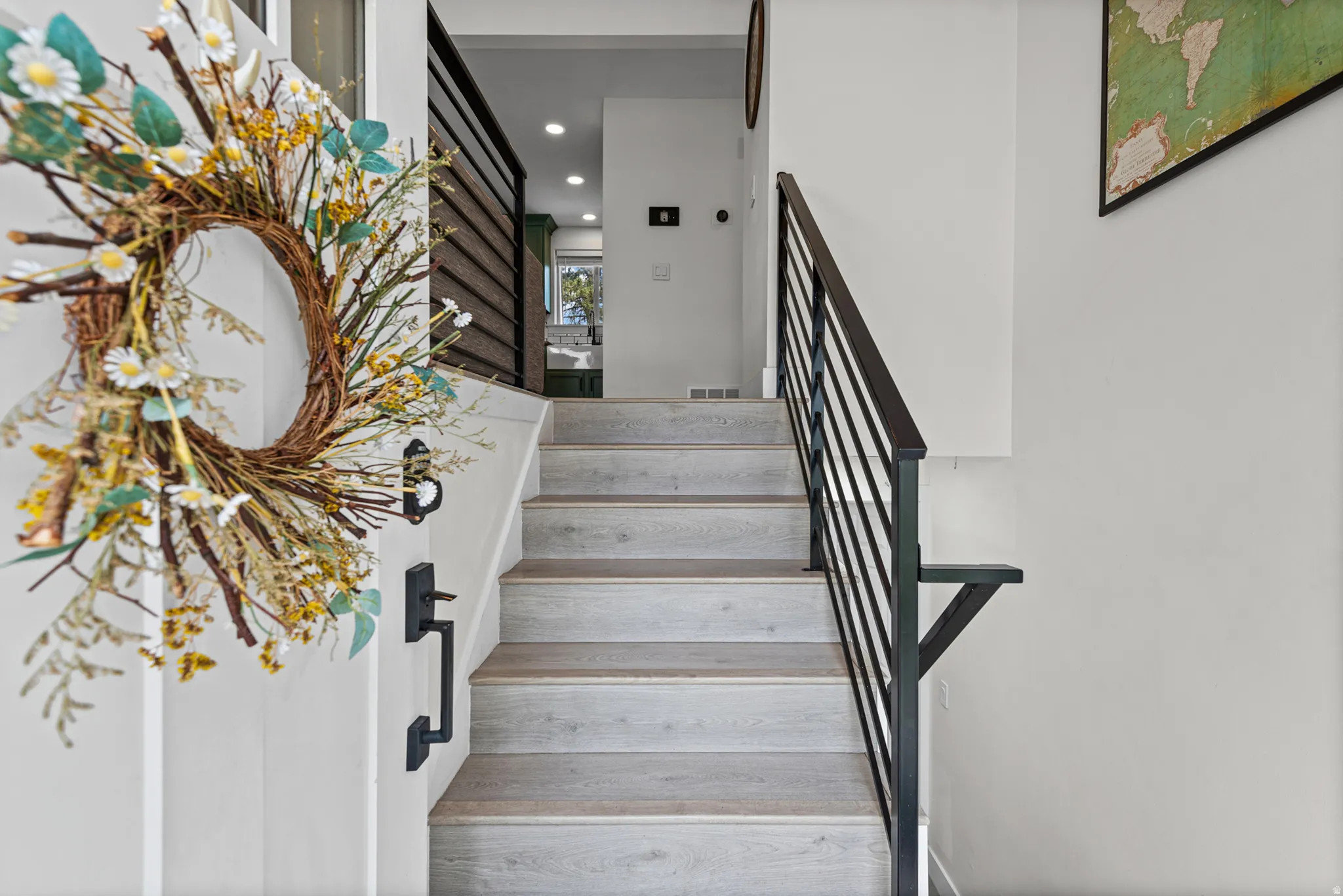 Staircase featuring wood-finish treads and risers with a contemporary black metal railing